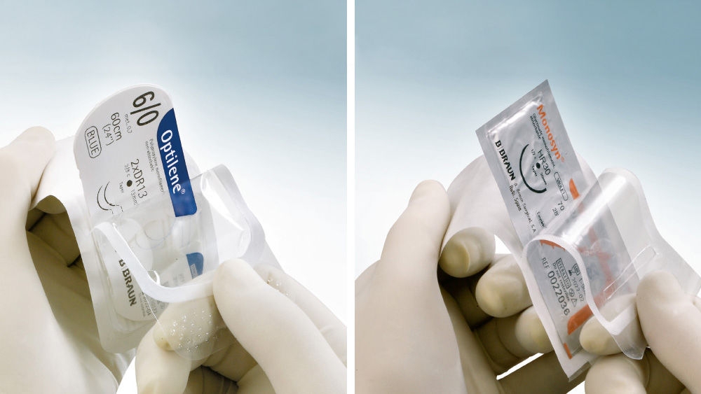 Je zwei behandschuhte Hände halten jeweils Nahtmaterialverpackungen in transparenter Blisterverpackung, nebeneinander dargestellt. Die linke Verpackung ist mit „Optilene® 6/0“, blau, 60 cm beschriftet, die rechte Verpackung mit „Monosyn®“, beide mit B. Braun Branding, vor einem hellblauen Hintergrund.