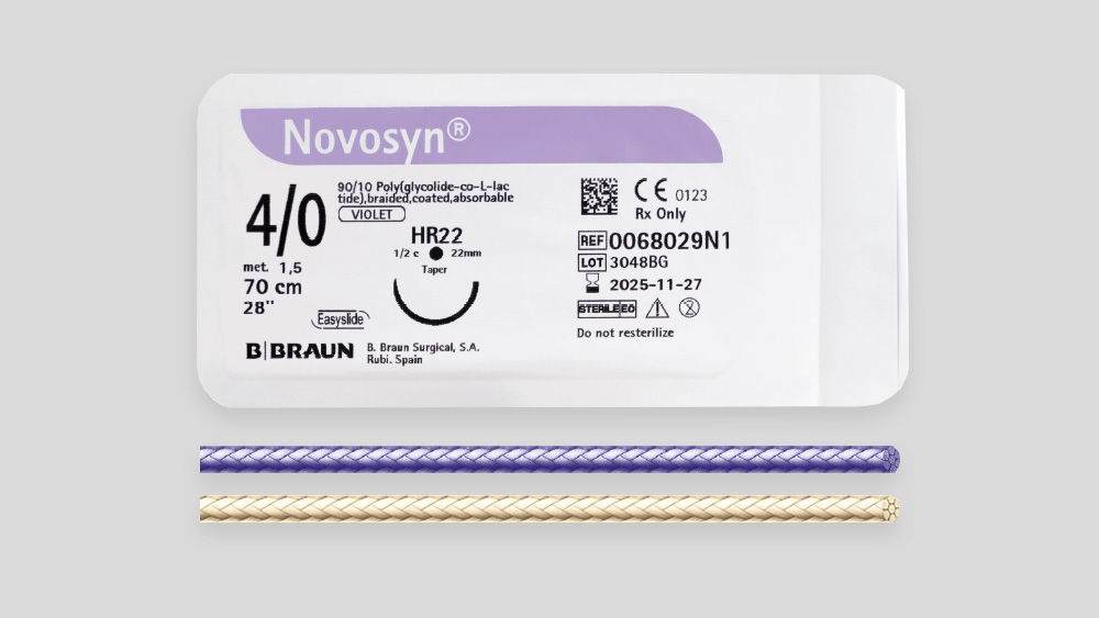 Verpackung der resorbierbaren Naht Novosyn® unter der Überschrift „Eigenschaften und Merkmale“, mit Produktetikett mit Angabe von Fadenstärke (USP 4/0), Nadeltyp, Nahtlänge, CE‑Kennzeichnung und B. Braun Branding sowie dem unterhalb der Verpackung sichtbaren geflochtenen Nahtfaden