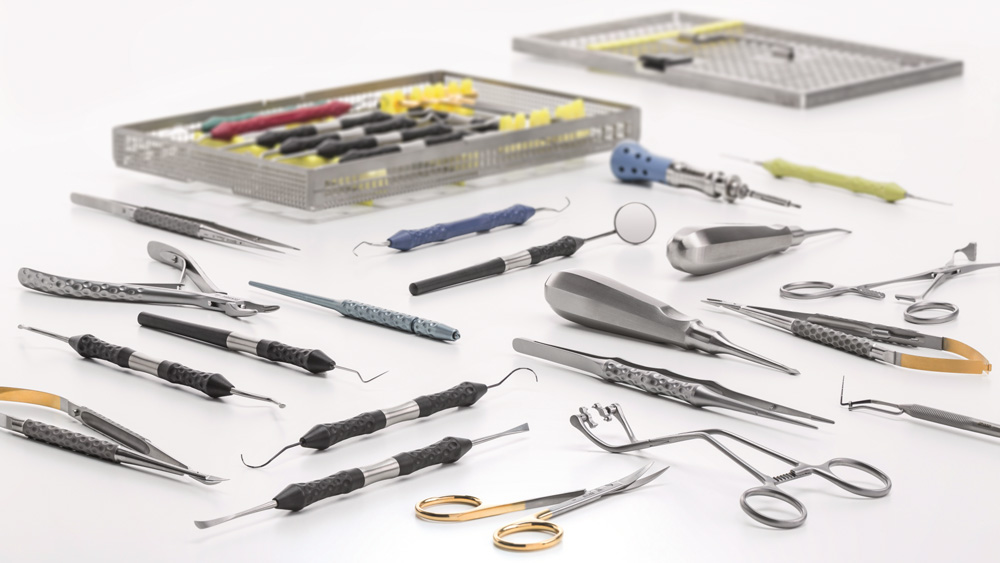 Sortiment an dentalen Instrumenten und Geräten, ausgelegt auf einer weißen Oberfläche neben einer geöffneten Aufbewahrungsschale.